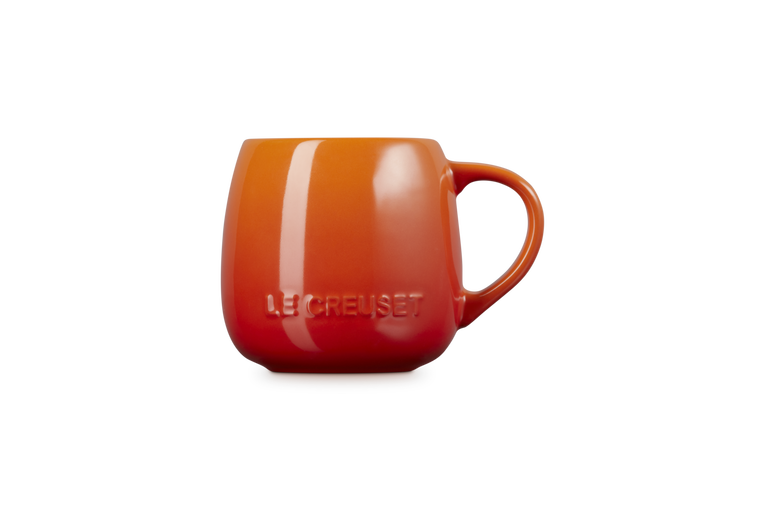 Le Creuset Coupe Mug in volcanic orange with embossed logo and rounded handle on white background.