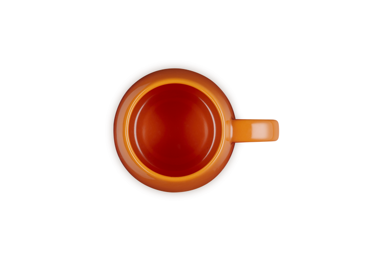 Le Creuset Coupe Mug in volcanic orange shown from top view with handle on the right side.