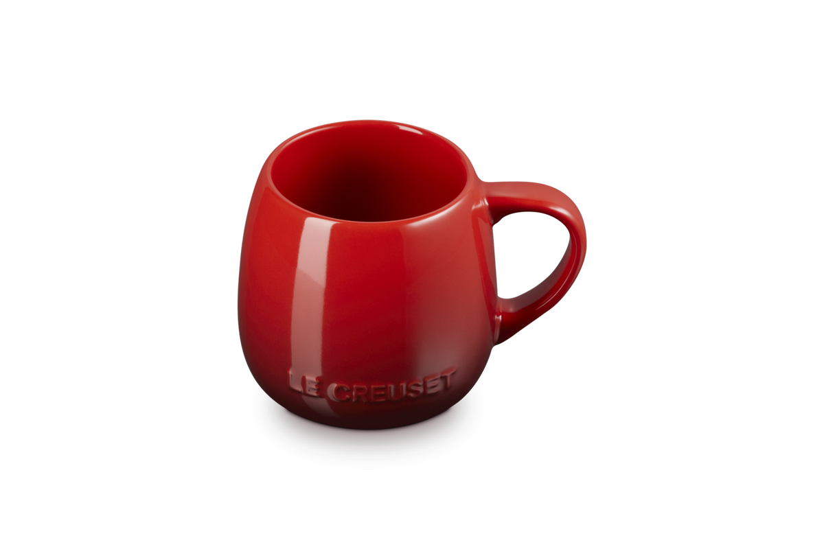 Glossy red Le Creuset 320ml coupe mug with embossed logo on the front and a rounded handle.