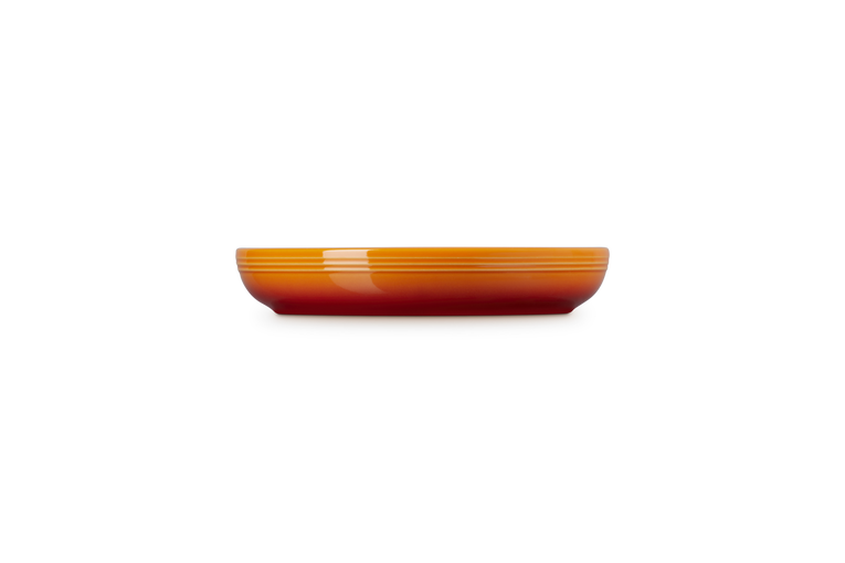 Le Creuset Coupe Pasta Bowl in volcanic orange shown from side on black background.