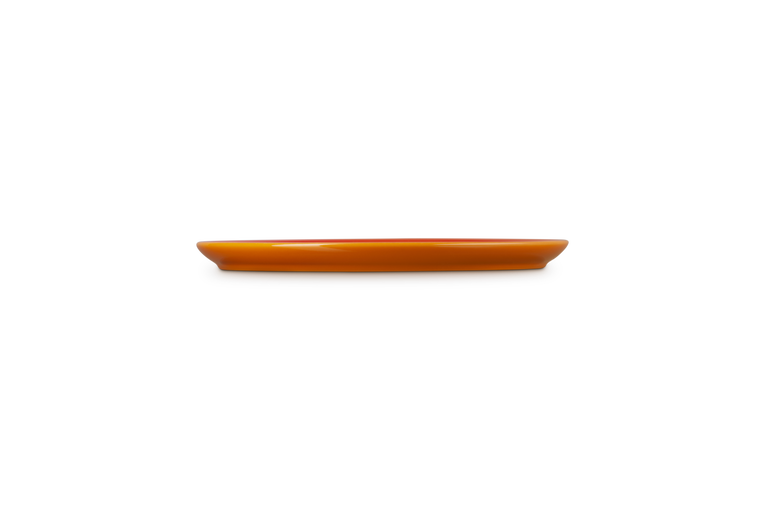 Le Creuset Coupe Side Plate in volcanic orange, shown from a side profile on black background.