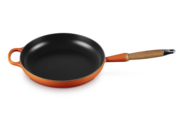 Le Creuset Signature 28cm cast iron frying pan in volcanic orange with wooden handle, top view.