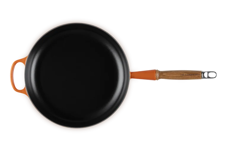 Le Creuset Signature 28cm cast iron frying pan in volcanic orange with wooden handle, top view.