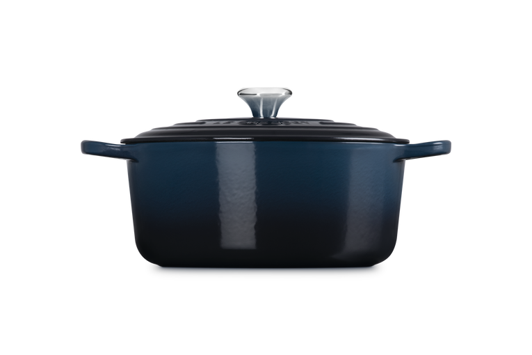 Le Creuset 28cm round casserole in deep blue with lid and silver knob, side view on white background