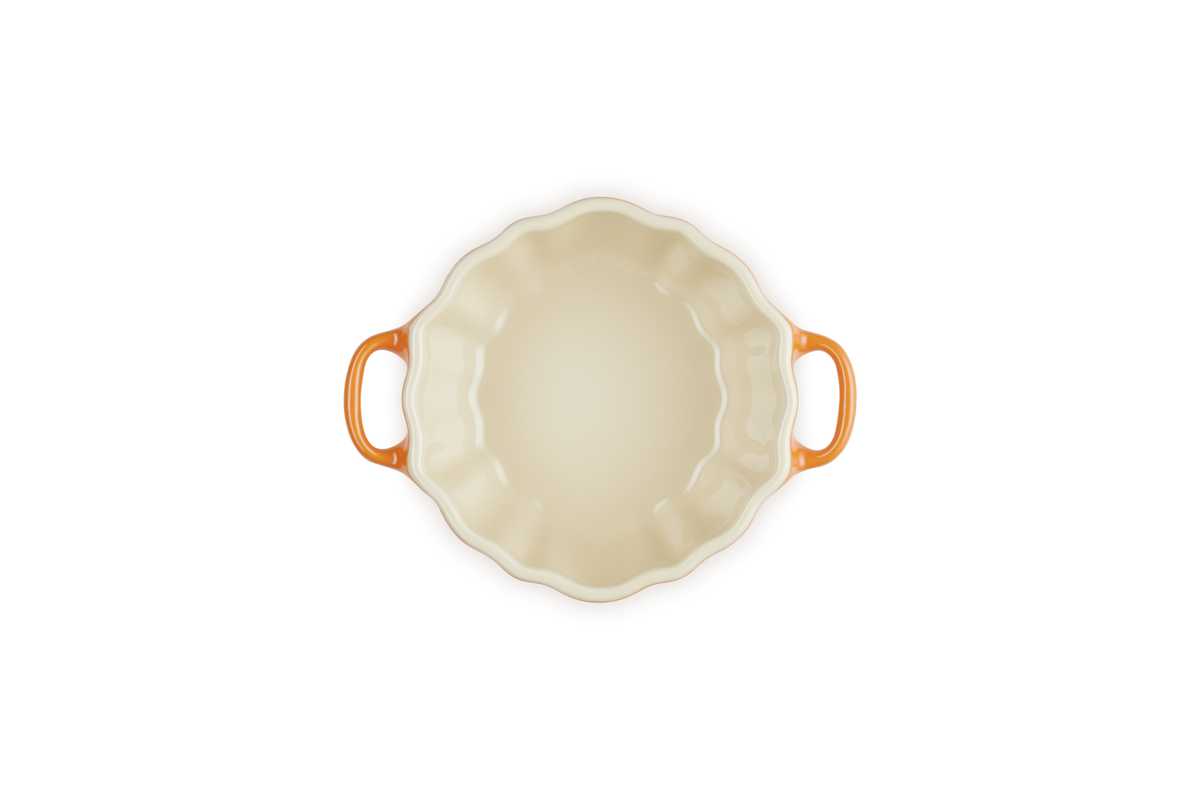 Top view of Le Creuset Halloween Pumpkin casserole dish in volcanic orange with scalloped edges and two handles.