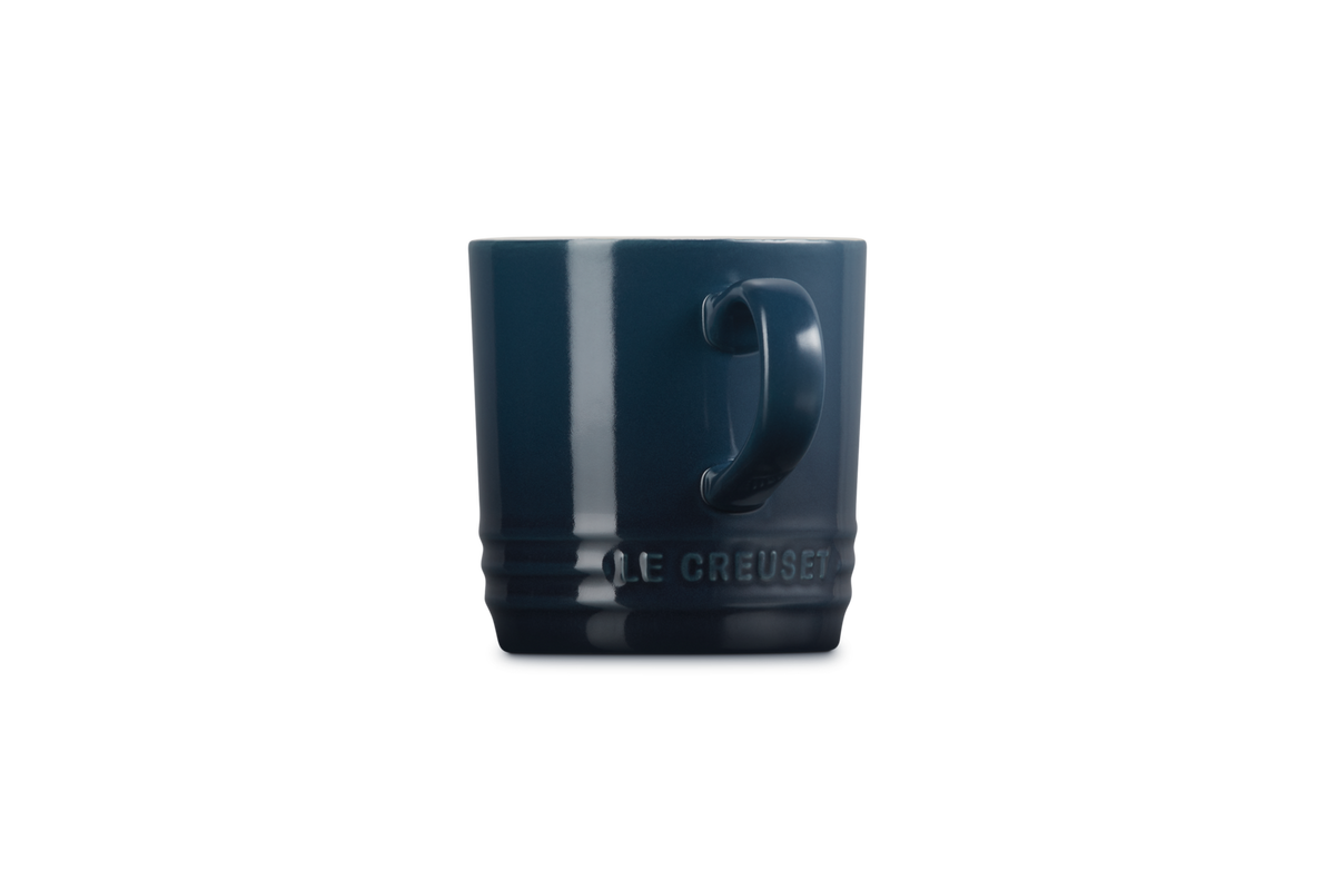 Le Creuset Cappuccino Mug in deep blue, side view showing handle and embossed logo.