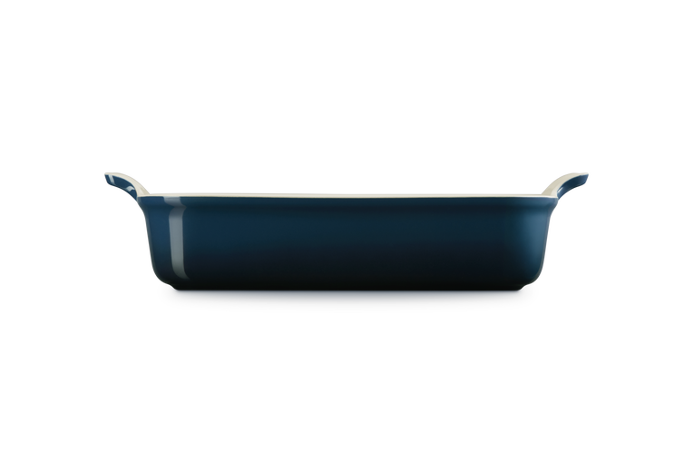 Le Creuset rectangular deep dish in Nuit blue, shown from side with handles visible.