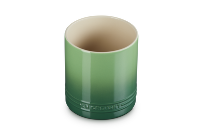 Le Creuset small utensil jar in gradient green ceramic with bamboo lid beside it on white background.