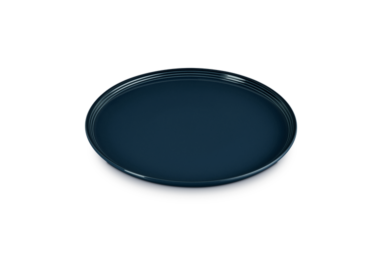 Le Creuset Coupe Dinner Plate in deep navy blue with a smooth, glossy finish and subtle ridged edge.