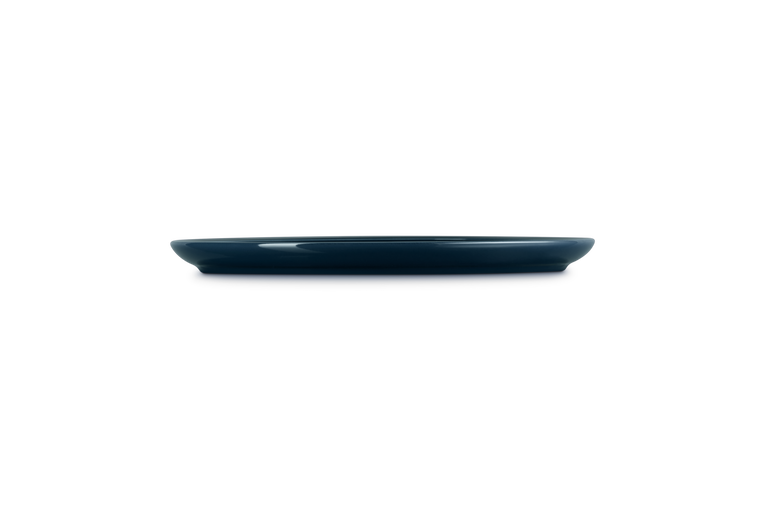 Le Creuset Coupe Dinner Plate Nuit shown from side, highlighting its slim profile and deep blue color.