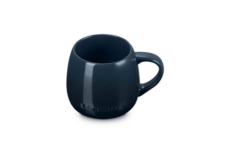 Le Creuset Coupe Mug in deep navy blue with rounded shape and embossed logo on front.