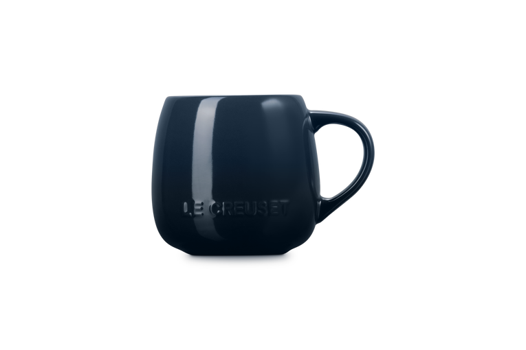 Le Creuset Coupe Mug in deep navy blue with embossed logo on the side, shown from the side.