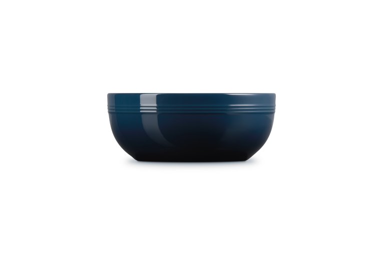 Le Creuset Coupe Serve Bowl in deep blue, shown from the side on a white background.