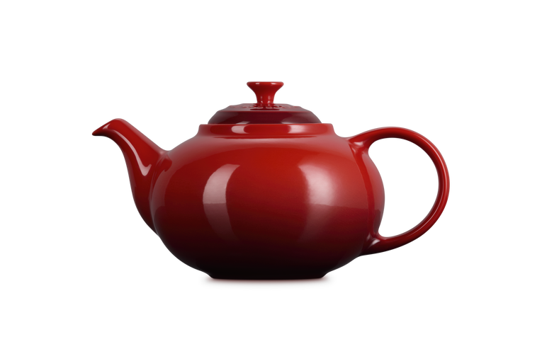 Le Creuset Cerise red stoneware teapot with rounded body, curved spout, and handle, shown from the side.
