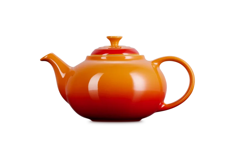 Le Creuset Stoneware Classic Teapot in volcanic orange with lid, side view on white background.