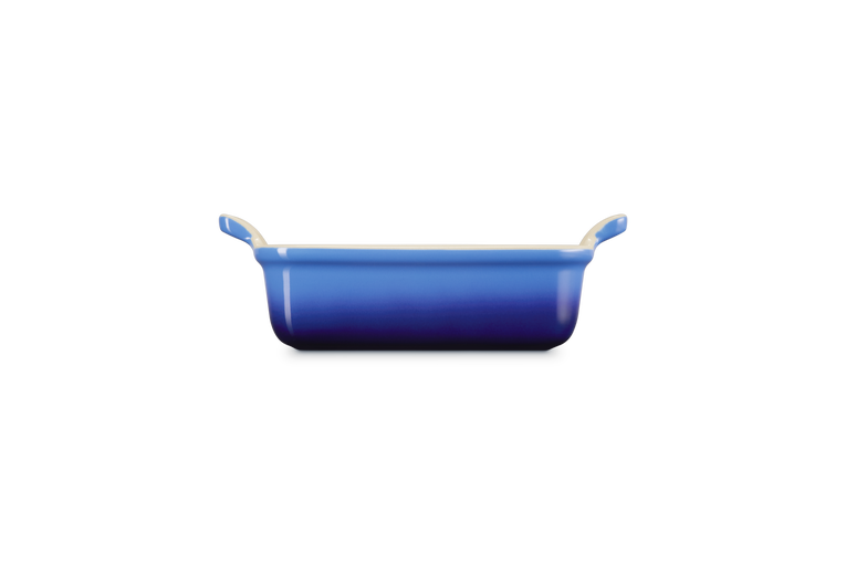Le Creuset rectangular stoneware dish in azure, shown from side with handles visible.