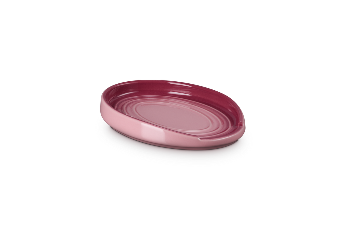Le Creuset oval spoon rest in rose quartz with a glossy finish and concentric ring design.