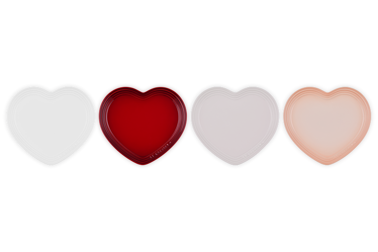 Four heart-shaped plates in white, red, light pink, and peach from the Le Creuset Heart Set.