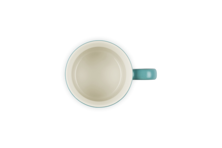 Top view of a blue Riviera Le Creuset Cappuccino Mug with a cream interior, empty and handle on the right.
