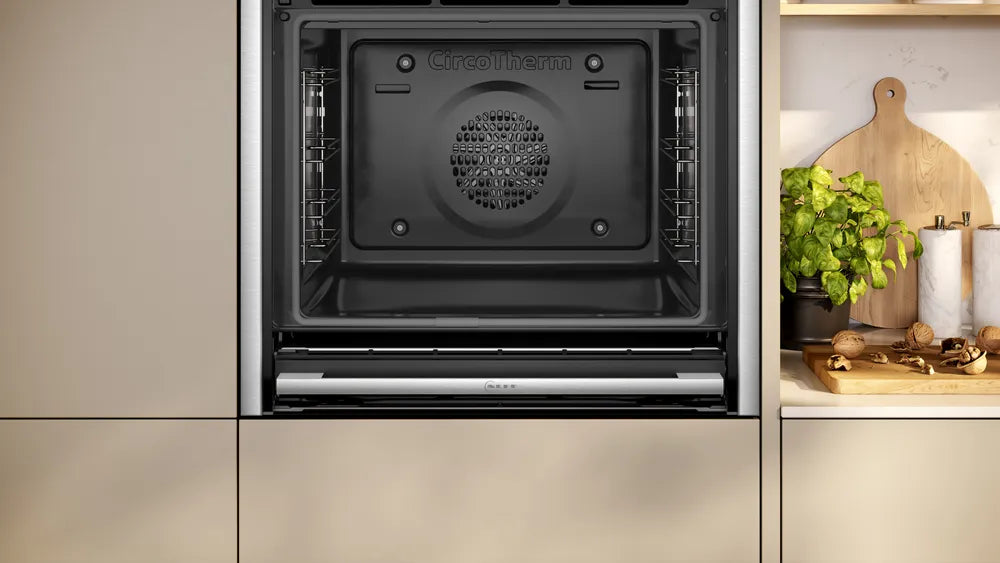NEFF N70 Slide&Hide B54CR71N0B stainless steel oven with open door showing interior fan and racks in kitchen setting