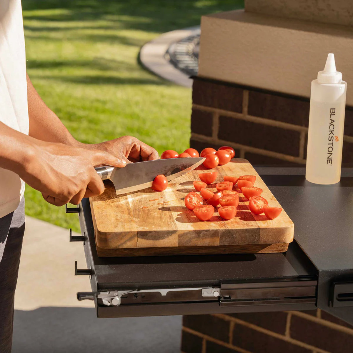 Blackstone Forged Blackout 36" Griddle side shelf with cutting board and tomatoes being sliced outdoors