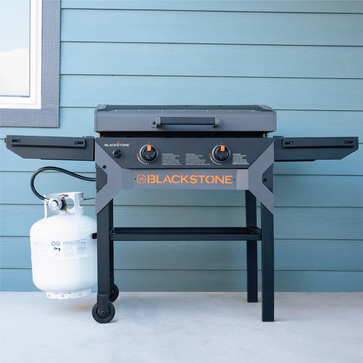 Blackstone 28" iron forged griddle with hood, side shelves, control knobs, and attached propane tank