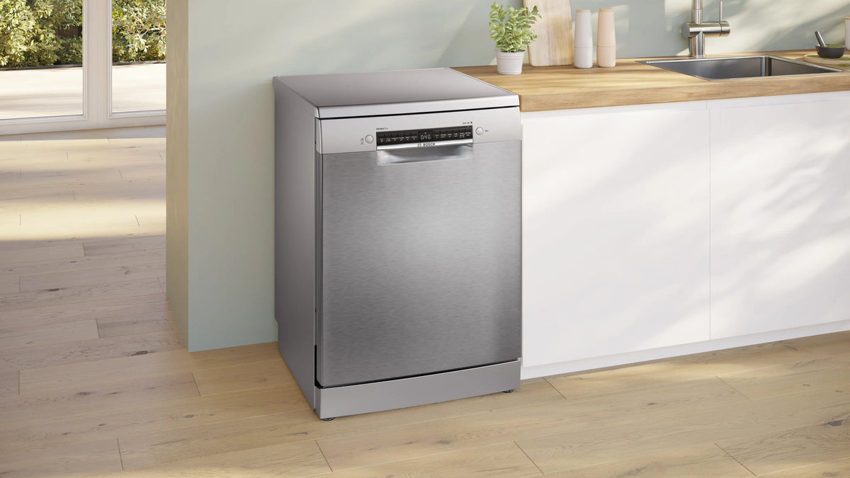 Bosch Series 6 freestanding 60cm dishwasher in stainless steel, placed next to a kitchen counter with sink and decor.