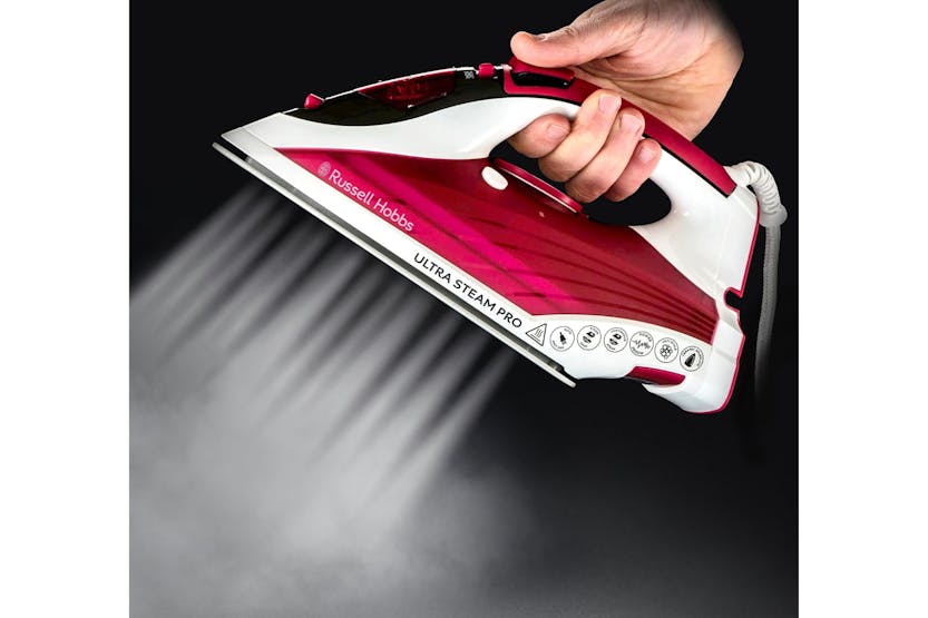Hand holding Russel Hobs Glide Steam Iron releasing steam from the soleplate against a black background