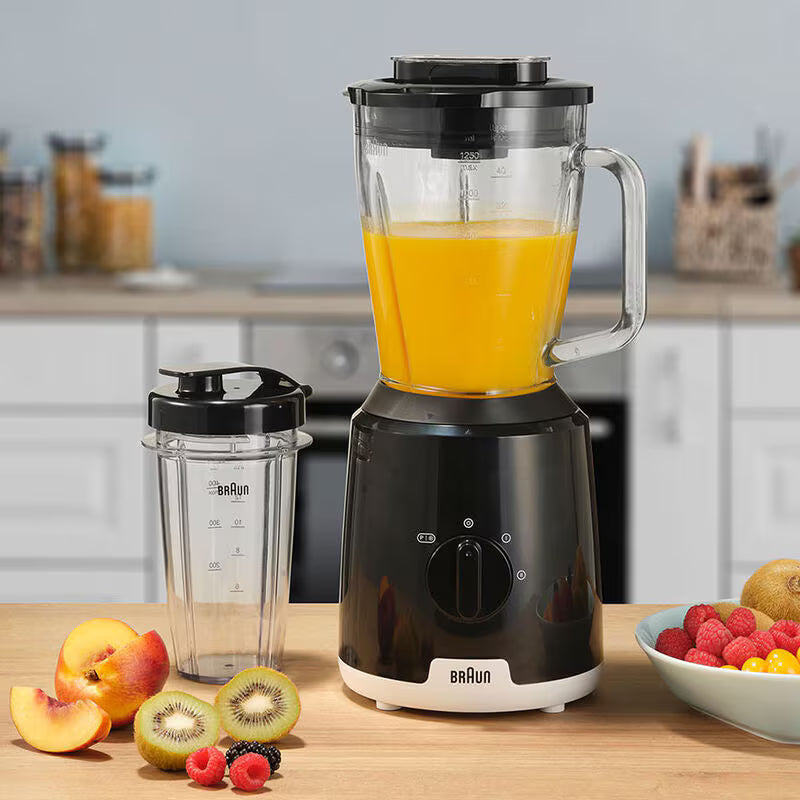 Braun Power Blender JB1051BK with orange juice in pitcher, extra blending cup, and fresh fruit on kitchen counter