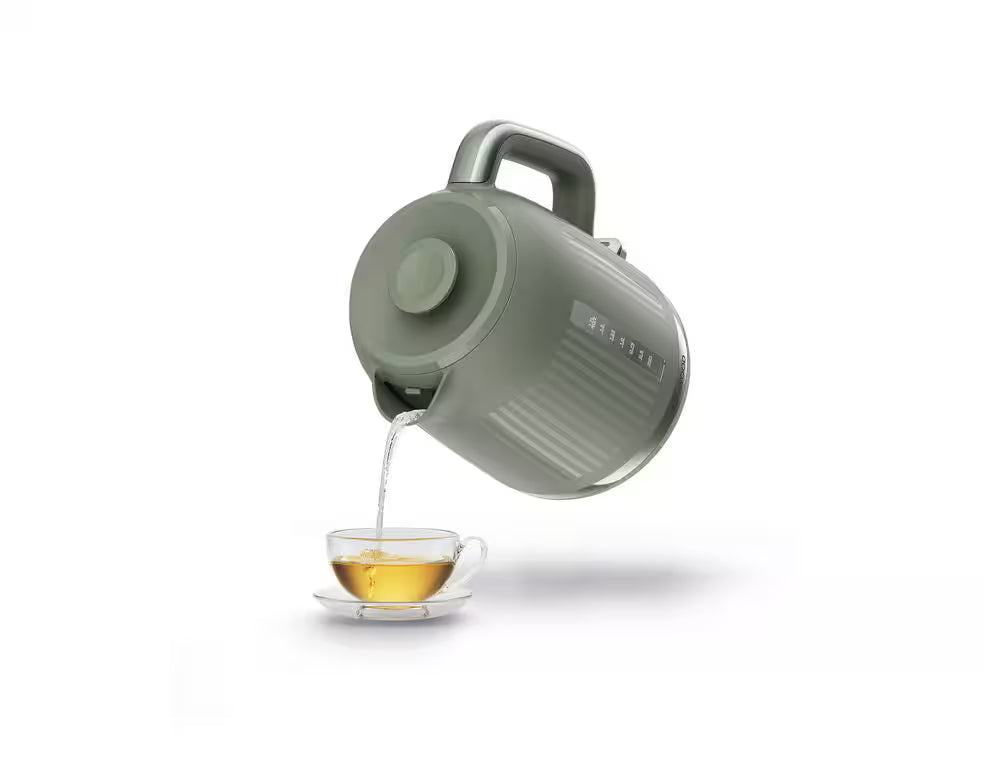 Kenwood Dusk Collection green kettle pouring hot water into a glass cup with saucer on white background
