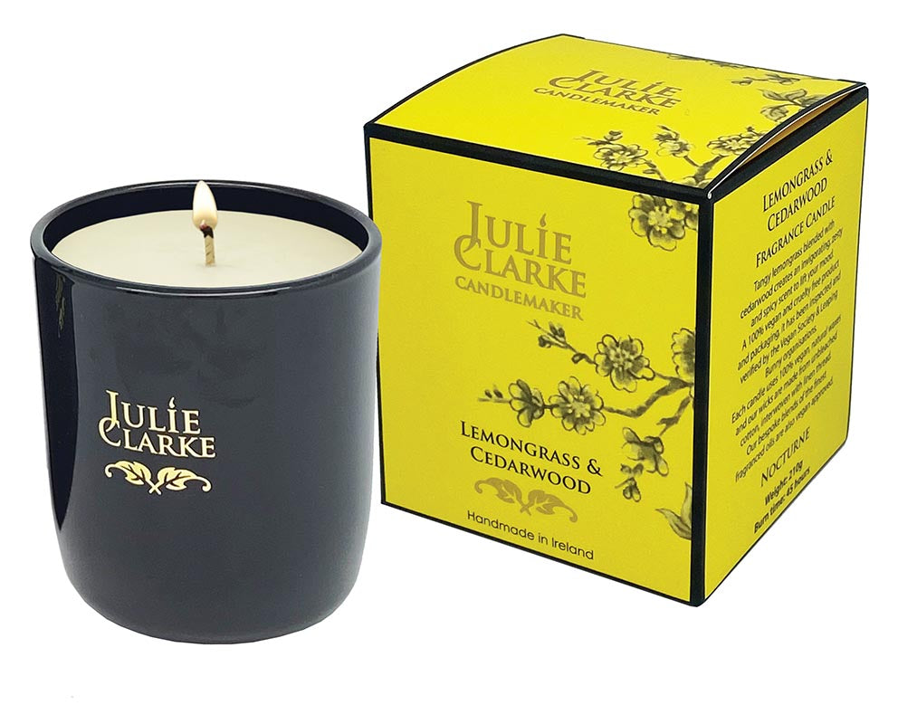 Julie Clarke Nocturne candle lit in black glass next to yellow Lemongrass & Cedarwood gift box