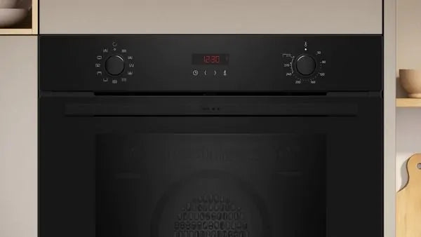Neff B2DCG7AK3B built-in black electric single oven with control knobs and digital display in a kitchen setting.