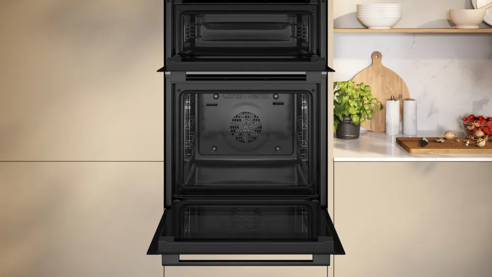 Neff N50 CircoTherm double oven in graphite with both oven doors open, built into kitchen cabinetry.
