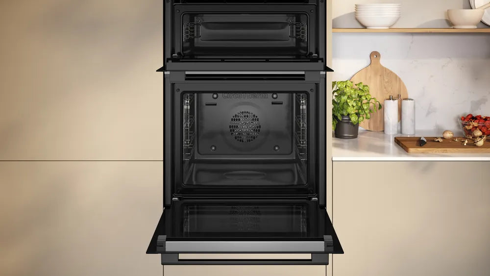 Neff 50 built-in double oven with open lower door, showing empty interior and kitchen countertop background.