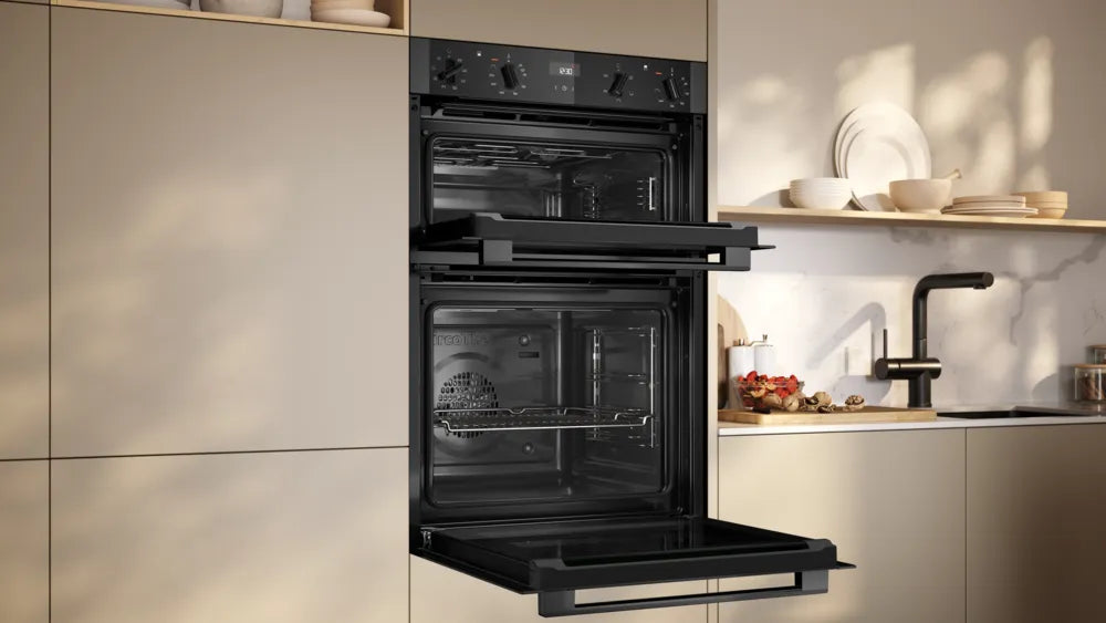 Neff N50 CircoTherm double oven in graphite with both doors open, built into beige kitchen cabinetry.