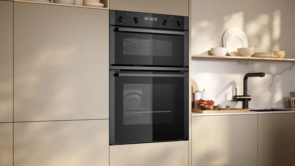 Built-in Neff 50 double oven with black glass doors and control knobs in a modern kitchen setting.