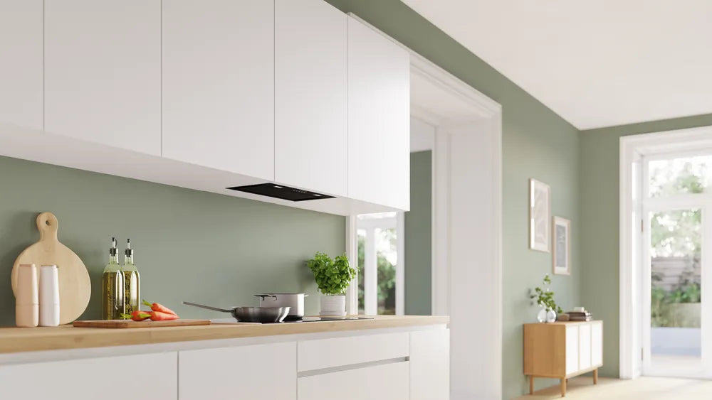 Bosch Series 6 black canopy cooker hood installed under white kitchen cabinets above a wooden countertop.