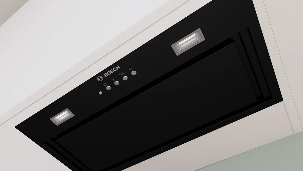Black Bosch Series 6 canopy cooker hood installed under a white kitchen cabinet with control buttons and lights visible.