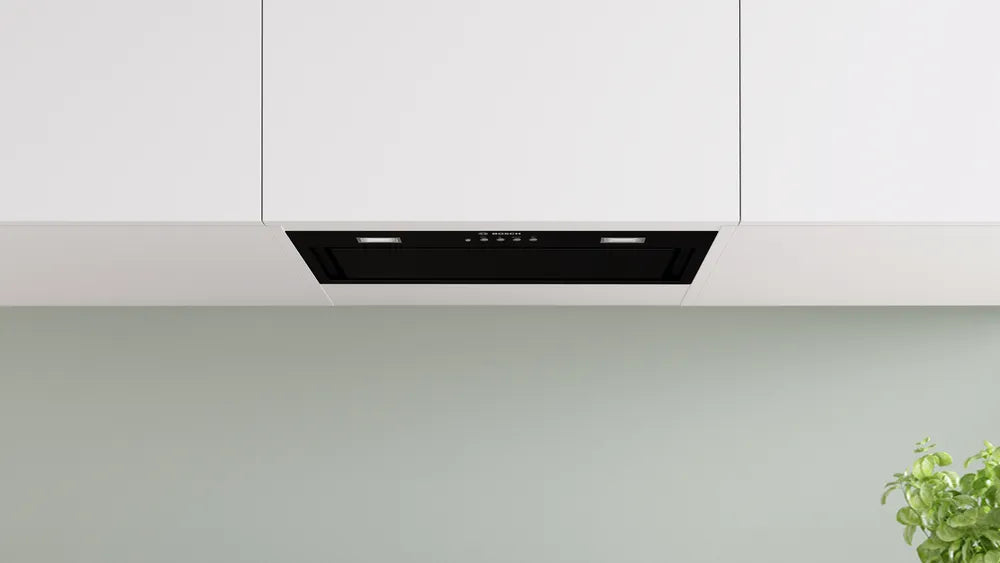 Black Bosch Series 6 canopy cooker hood installed under white kitchen cabinets with control panel and lights visible.
