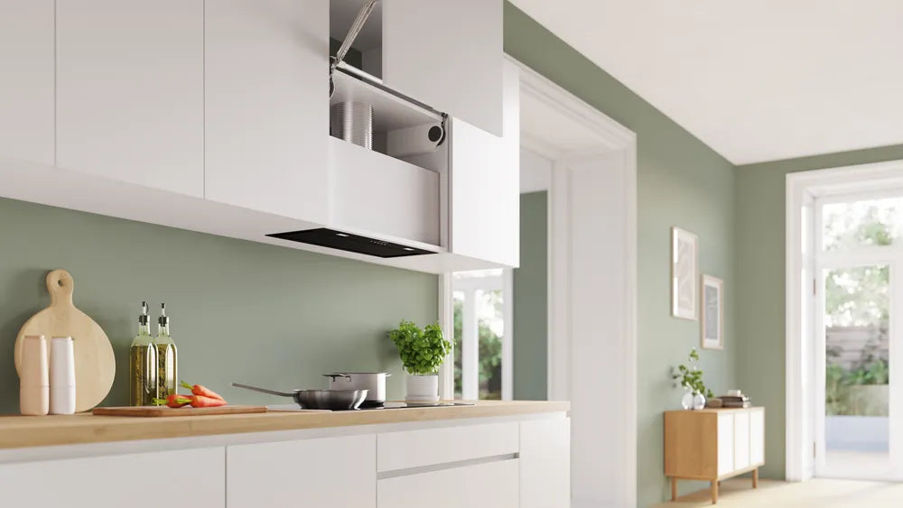 Bosch Series 6 black canopy cooker hood extended from white kitchen cabinets above a stove with pots and herbs.