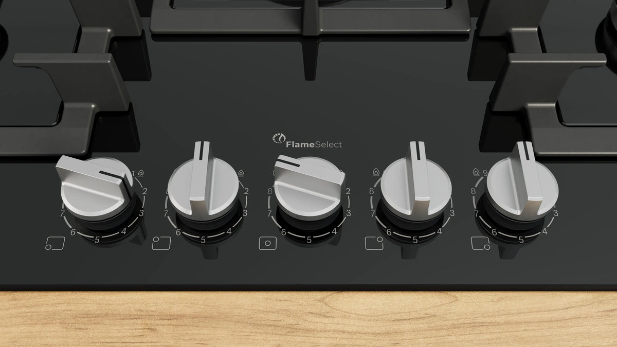 Close-up of Bosch 75cm black gas hob control knobs on glass surface with FlameSelect branding.