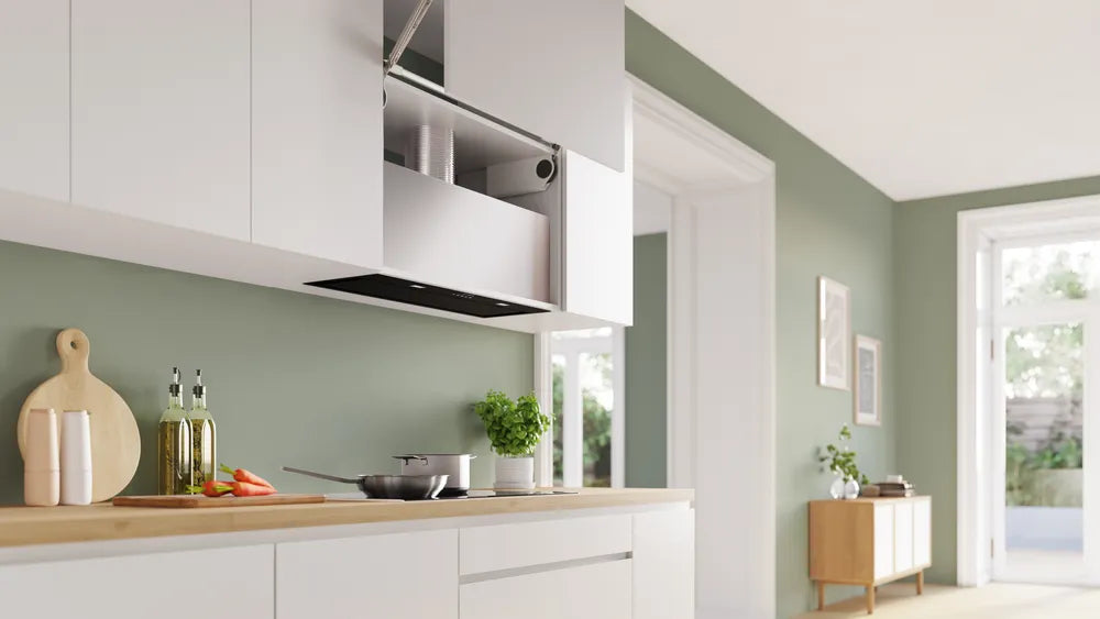 Bosch Series 6 black canopy cooker hood installed under white kitchen cabinets above a stove with cookware and herbs.