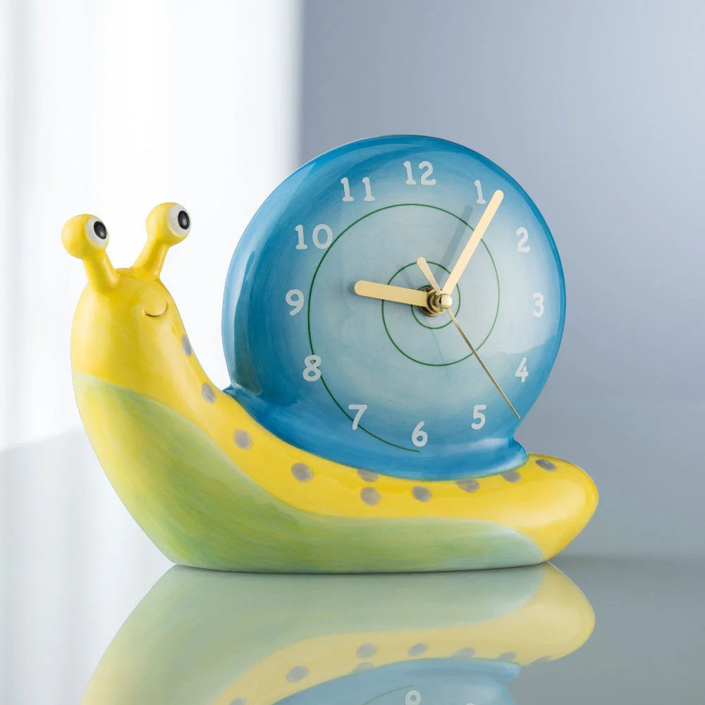 Yellow and green snail-shaped table clock with a blue spiral shell clock face showing 9:05:25