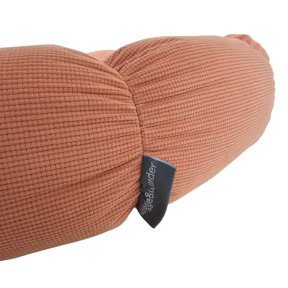 Close-up of pink textured fabric and Wiggle & Wander label on Flower Pet Bed cushion