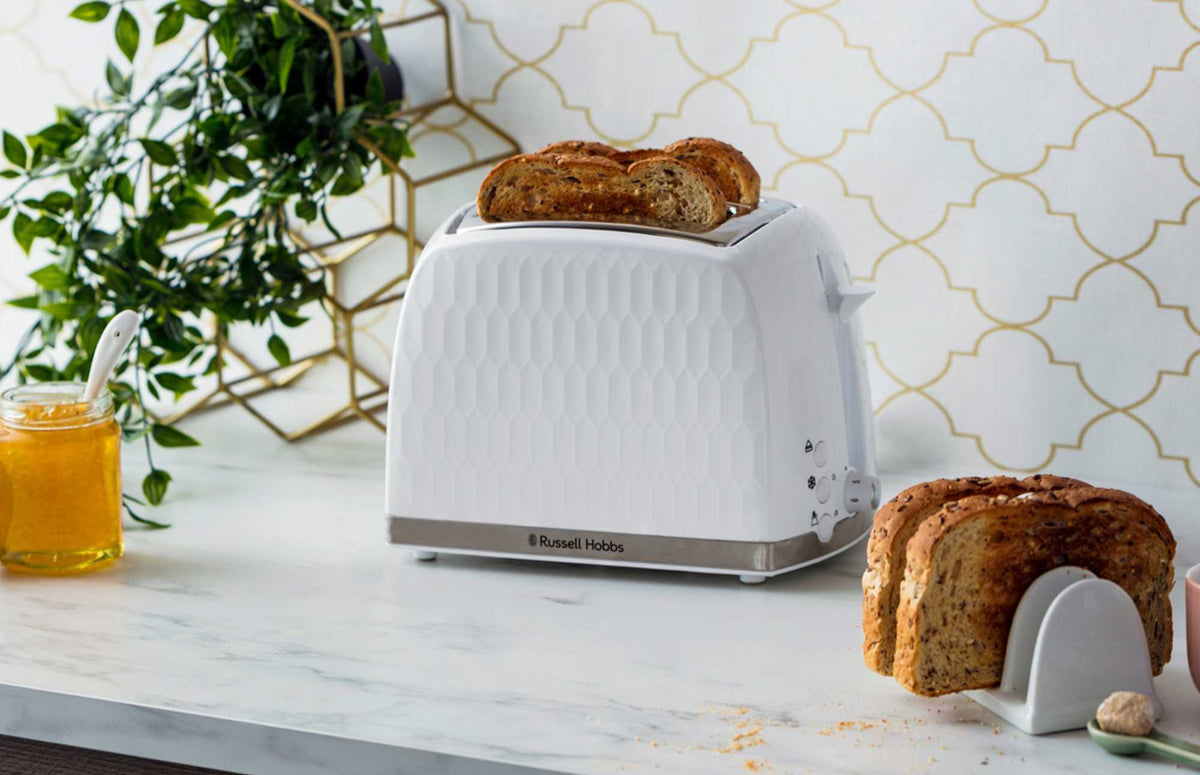 White Russell Honeycomb Hobbs toaster with two slices of seeded bread inside on a marble countertop
