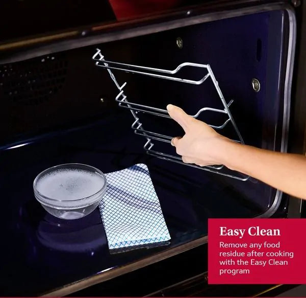 Hand removing oven rack inside Neff B2DCG7AK3B built-in electric oven with cleaning cloth and bowl inside.