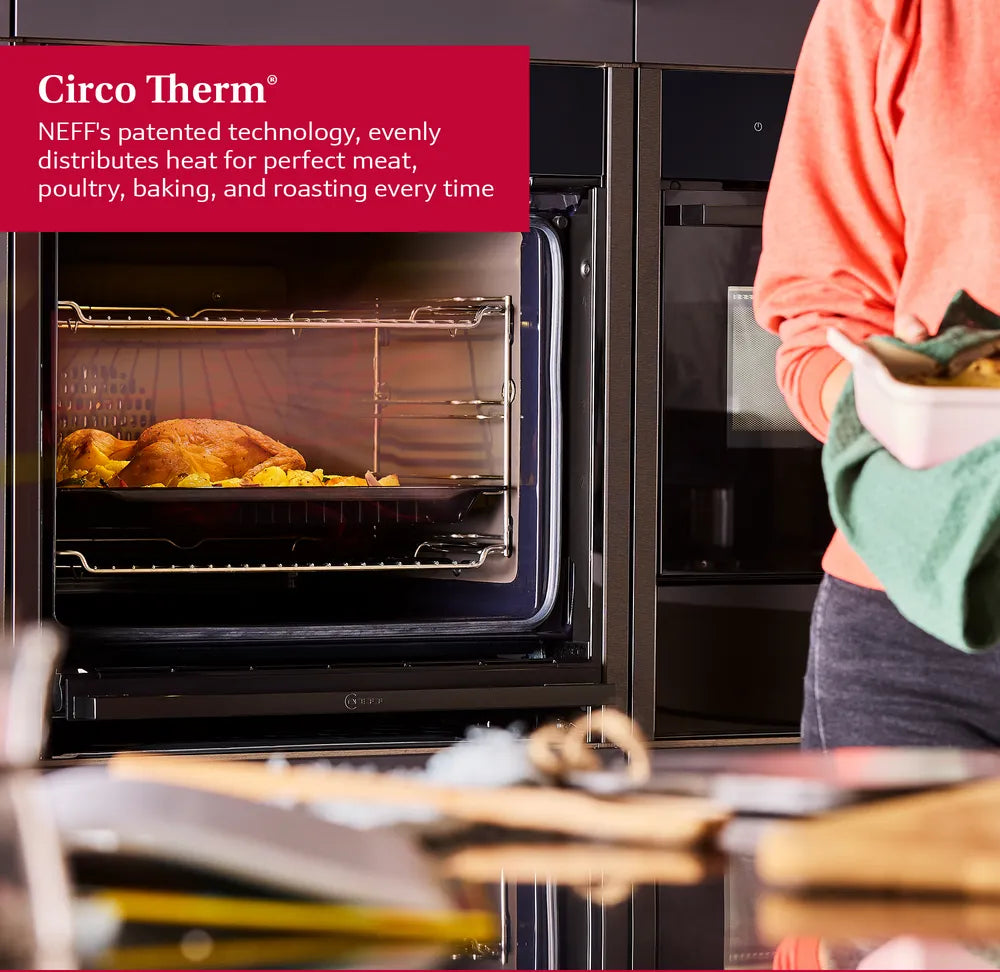 Neff N50 built-in oven with roasted chicken and potatoes inside, person holding dish nearby