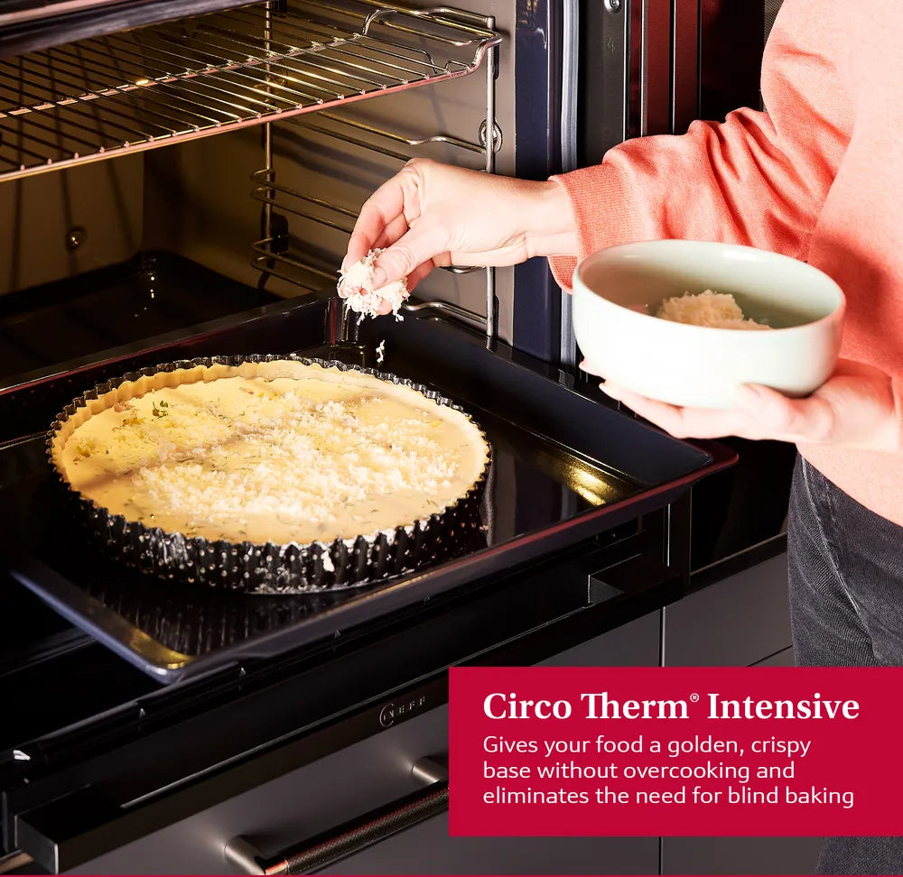 Person sprinkling cheese on a tart inside a stainless steel Neff N50 built-in oven with open door.