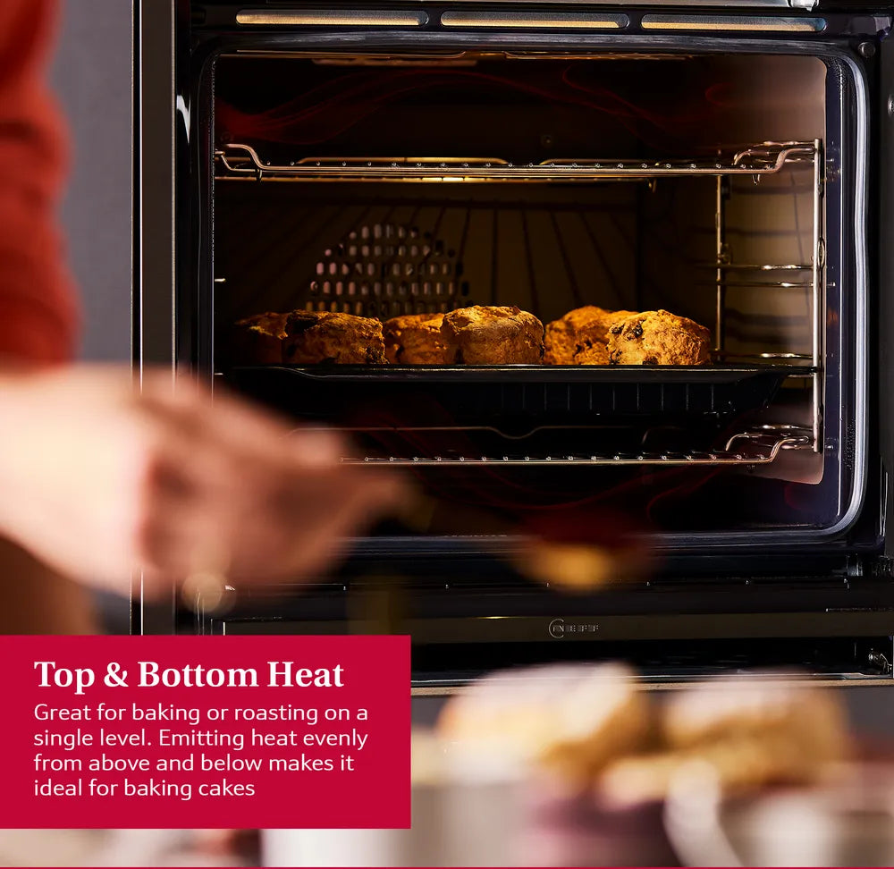 Neff N50 built-in stainless steel oven baking scones on a tray with door open and hand nearby