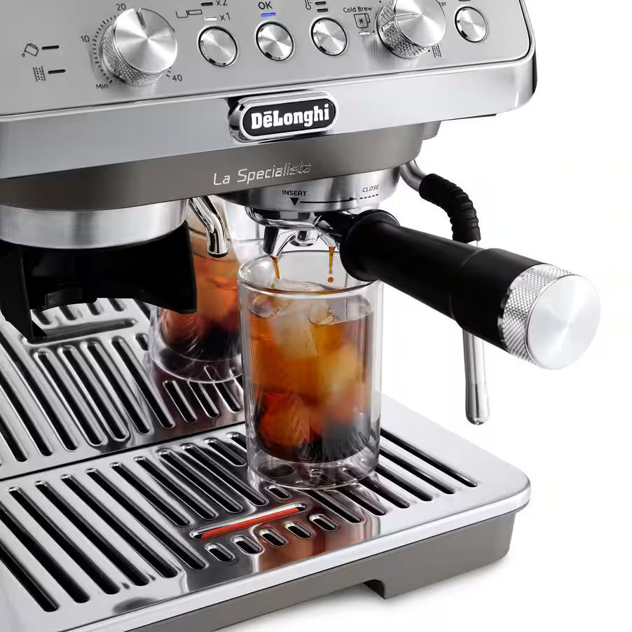 DeLonghi La Specialista Arte Evo espresso machine pouring coffee into a glass with ice on a stainless steel drip tray.